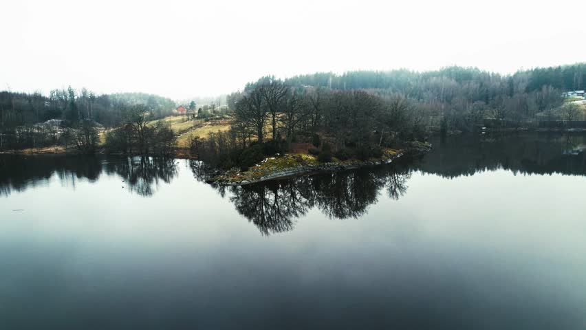 Tranquil island on calm lake reflecting serene atmosphere, Aerial parallax