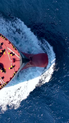 Aerial overhead view of a bow from a large container cargo or tanker ship sailing with speed over the ocean
