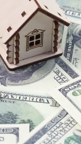 Mortgage concept. Wooden model of house and on dollar banknotes background rotate