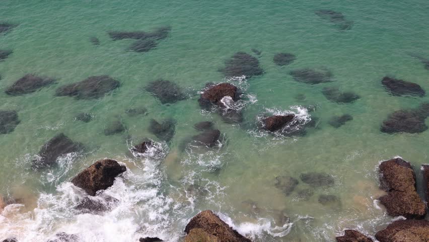 waves washing over rocks from above with blue green water tones
