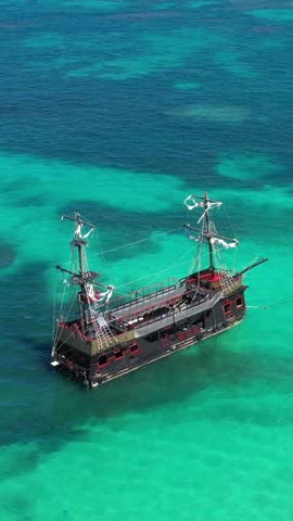 Pirate ship floating in caribbean sea. It is popular excursion for tourists. Dominican Republic. Aerial top view. Vertical footage