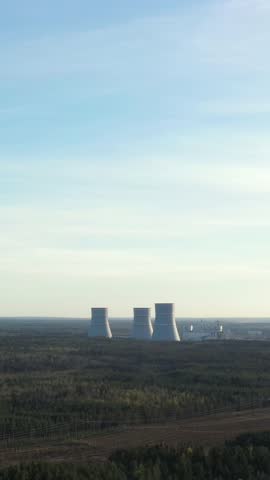 Aerial view on smoking cooling towers at nuclear power plant. Vertical footage