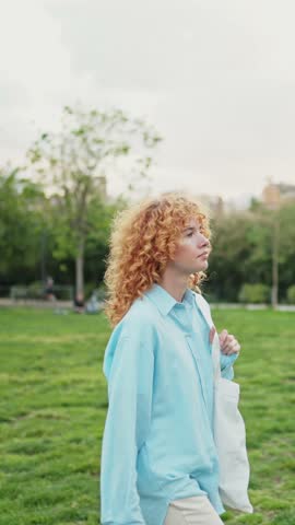 Young redhead woman walking in park looking up in slow motion
