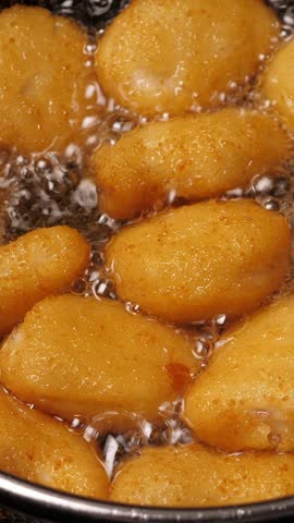 Cooking tempura chicken nuggets in deep fryer. Vertical footage