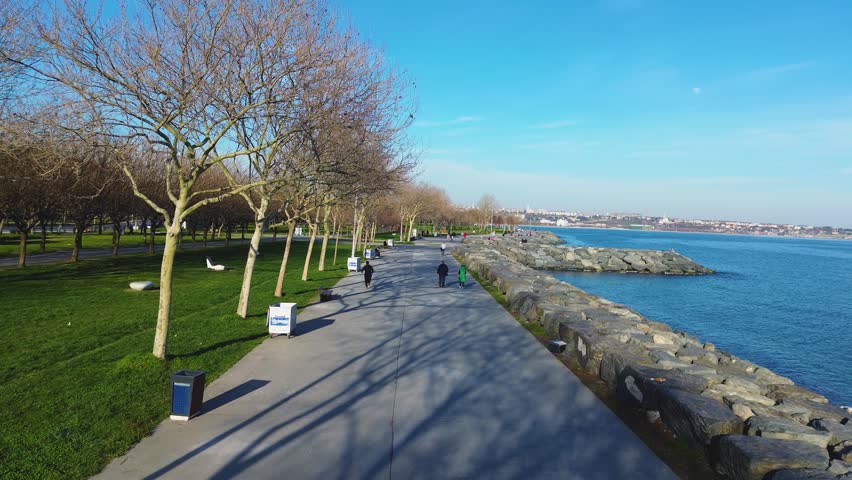Sunny day on a pedestrian promenade with lamp posts and sea view in Istanbul.
