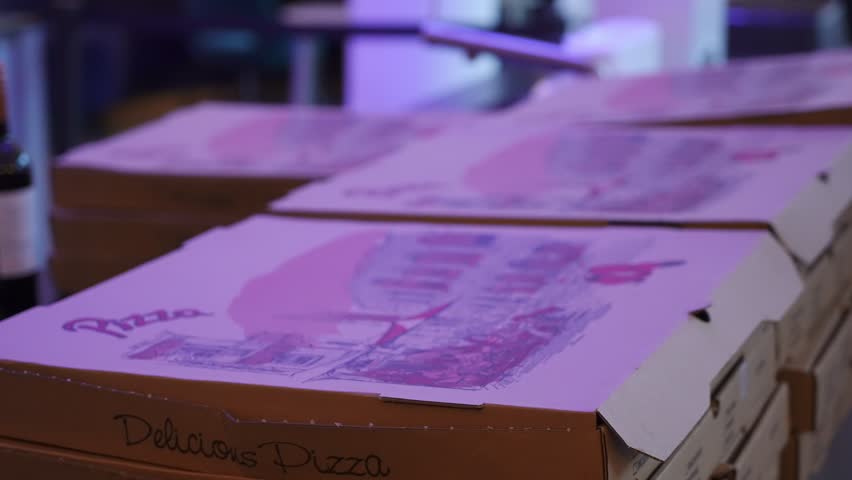A vibrant stack of colorful pizza boxes is eagerly awaiting delivery in a lively and bustling setting