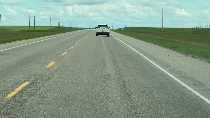 Scenic Highway Drive Through Open Countryside with Blue Skies, Rolling Fields, and Distant Horizons in Alberta Canada During Summer