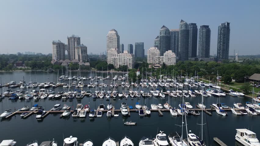 Aerial drone view of Humber Bay Park West in Toronto, showcasing docked boats, marina, and modern city skyline under clear blue sky.
