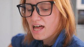 A young red-haired woman in glasses sits in a bright kitchen, singing and practicing guitar chords on her acoustic guitar. Warm natural light and casual atmosphere highlight a calm and focused moment  - Powered by Shutterstock - Get 15% off with code: PIKWIZARD15