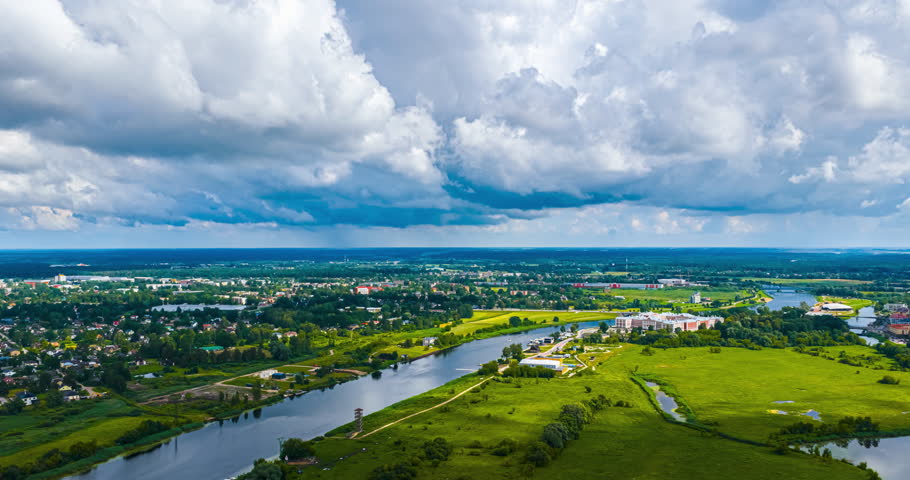 Aerial view of lush landscape and river under dramatic cloudy sky