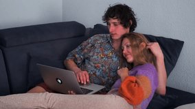 A couple cuddles on the couch, watching funny videos on a laptop. The woman laughs, pointing at the screen, while the man gently strokes her hair, enjoying a cozy, romantic evening together. - Powered by Shutterstock - Get 15% off with code: PIKWIZARD15