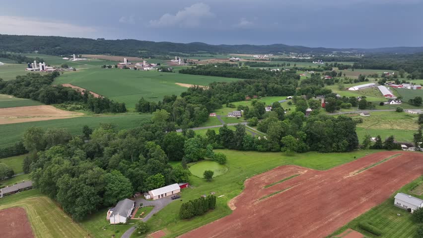 Hills landscape of American countryside in summer season. Aerial wide shot. Picturesque scenery of farmsteads in Nebraska, USA. Street of suburb neighborhood.
