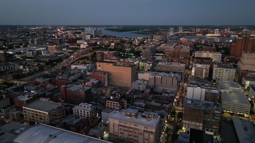 Traffic on interstate highway of Philadelphia st dusk. Descend drone shot. High-rise buildings and apartments in downtown. Wide shot. River and New Jersey state in distance. Night scene.