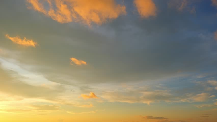 A sunset sky timelapse capturing nature’s gentle beauty as soft clouds glow with warm golden and orange hues against a fading blue sky. This embodies the calm, endless cycle of day turning to night.
