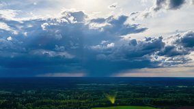 An epic aerial timelapse captures dramatic storm clouds, a rain shower, and beautiful sunbeams (god rays) shining down like a spotlight on a vast green forest. - Powered by Shutterstock - Get 15% off with code: PIKWIZARD15