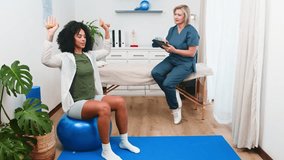A Dedicated Senior Physiotherapist Guides a Young Black Client Through Strength Training Exercises on a Stability Ball - Powered by Shutterstock - Get 15% off with code: PIKWIZARD15