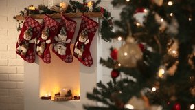 A cozy Christmas scene featuring a decorated fireplace with red stockings hanging. A Christmas tree adorned with lights and ornaments is visible in the background. - Powered by Shutterstock - Get 15% off with code: PIKWIZARD15