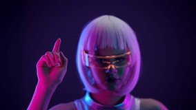 Stylish futuristic woman with white hair, holographic smart glasses, and shiny silver outfit interacting with a virtual interface. She is illuminated by neon pink and blue light in a dark background. - Powered by Shutterstock - Get 15% off with code: PIKWIZARD15