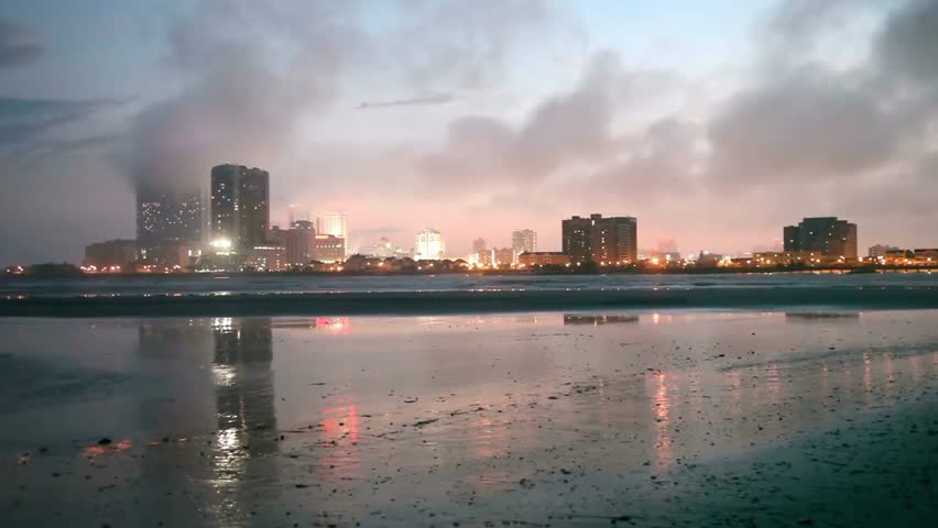 Atlantic city skyline reflecting in wet sand at dusk with cloudy sky