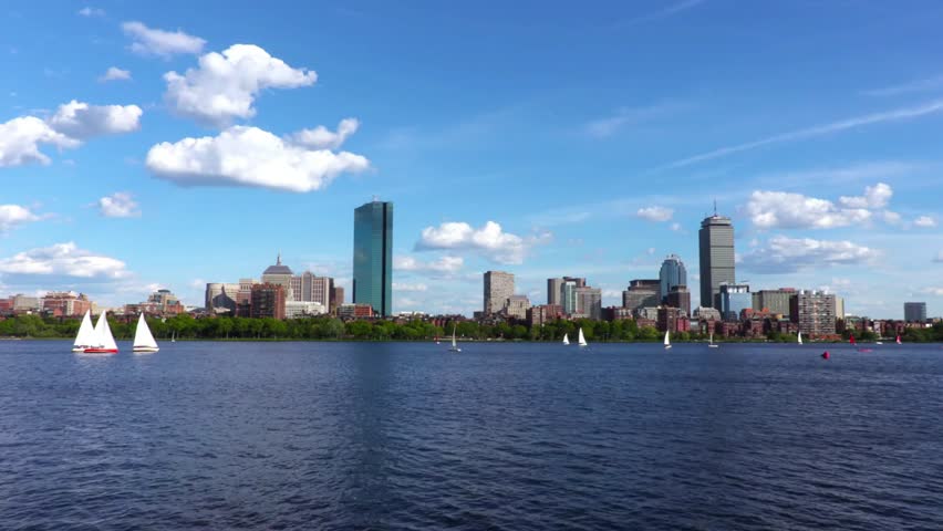 The boston massachusetts skyline on a sunny day with sailboats on the charles river