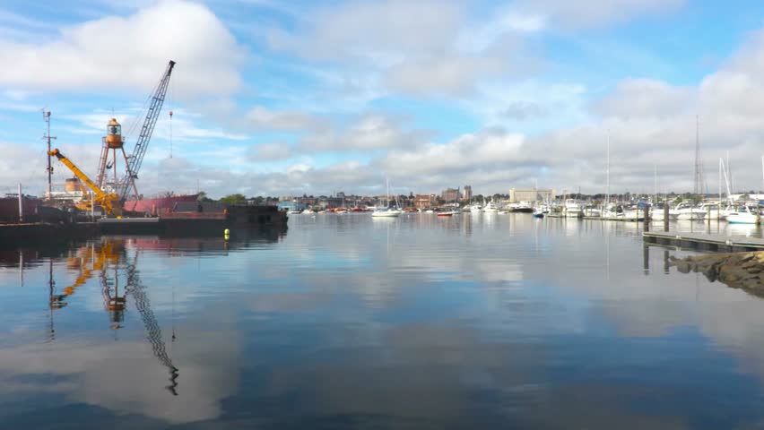 View of a harbor with cranes, boats, and buildings under a cloudy sky