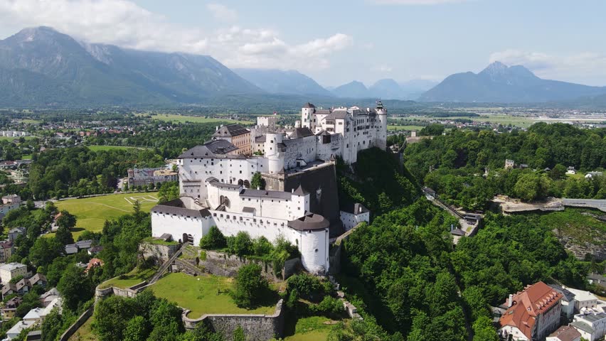 Towering medieval fortress stands proud above alpine valley and rooftops