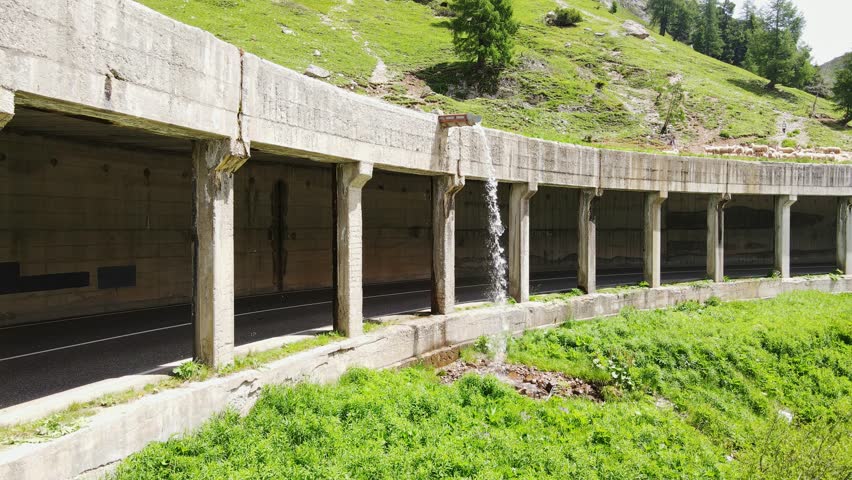 Alpine cyclist rolls under dripping tunnel beside Fedaia Lake near Marmolada