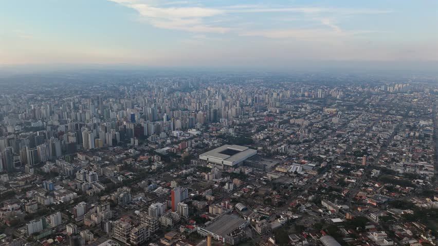 High drone view of Curitiba with Ligga Arena stadium surrounded by dense urban landscape.
