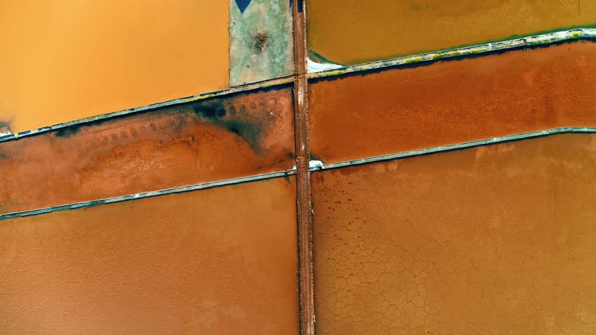 Drone view of salt marshes in bright sunshine. Top down view of colorful salt ponds on the Caribbean coast. Sea salt production in the Dominican Republic.