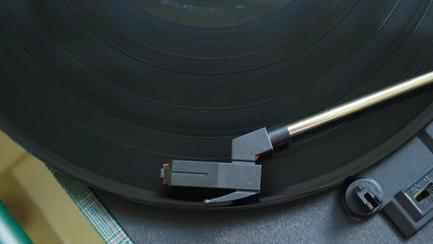 Top view of a vinyl record spinning on a turntable with the tonearm engaged in playback