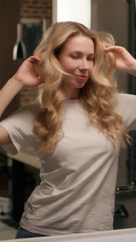 Playful flirty Caucasian woman girl enjoying self beauty appearance look mirror reflection female model flirting playing wellness skincare hairstyle morning routine confidence happiness home bathroom