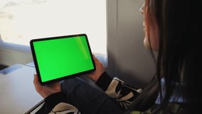 Hands holding a tablet with a green screen. A woman relaxes, spends time on the train on the way home or to work, or while traveling, watches videos and reads social networks or e-books. High quality - Powered by Shutterstock - Get 15% off with code: PIKWIZARD15