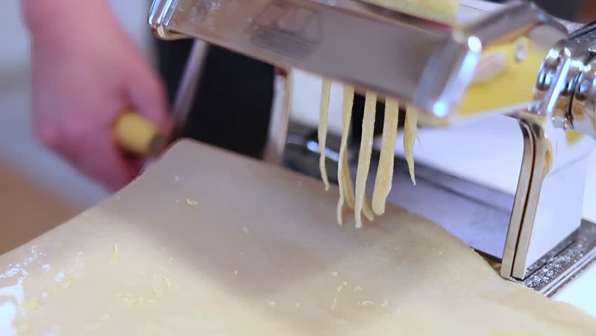 Golden Strands of Freshly Made Pasta Descend From The Machine
