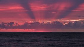 Stunning sunset over the ocean with crepuscular rays piercing through clouds, painting the sky in vibrant pinks and purples. A serene and dramatic seascape perfect for peaceful moments. Cinematic shot - Powered by Shutterstock - Get 15% off with code: PIKWIZARD15