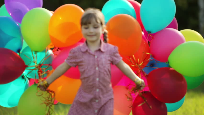 Child with balloons in the park. Girl looking at camera
