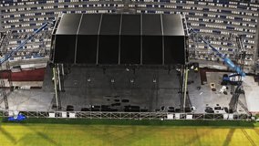 Music concert stage set up buildup construction. stadium football pitch being prepared to host a music concert. sports stadium as technicians set up the stage for the live music event. - Powered by Shutterstock - Get 15% off with code: PIKWIZARD15