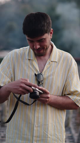 Young man checking pictures on his analog camera during a hike
