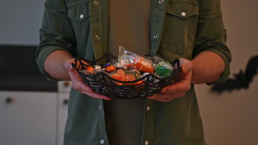 closeup of man holding halloween plate with candies for trick or treat