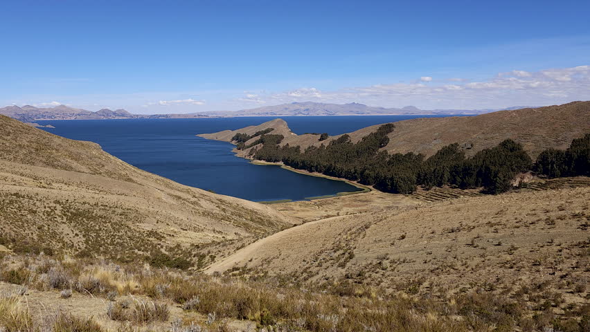 breathtaking panoramic view showcases the stunning Isla del Sol in Bolivia, surrounded by the deep blue waters of Lake Titicaca and framed by the majestic Andean landscape.