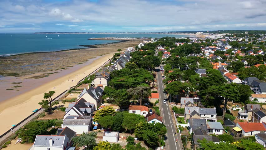 Forward drone movement over the Plage de Bonne-Source long coastal side with waterfront homes towards the Port de Plaisance harbor, Pornichet, Loire-Atlantique, France.