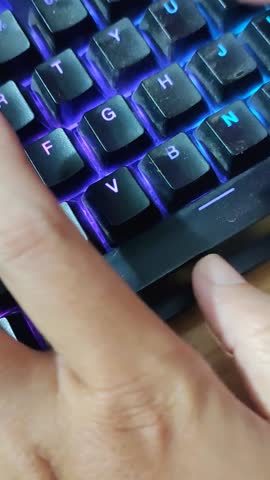 Vertical view of finger typing on RGB LED gaming keyboard