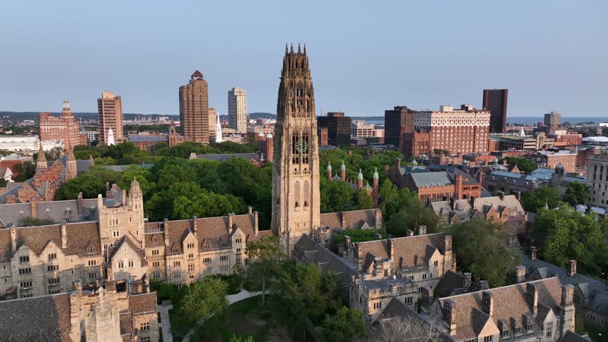 Aerial approaching shot of Harkness Tower at Yale old campus university of New Haven. American City in Connecticut at sunset. Summer day with green trees. Connecticut Financial Center In background.