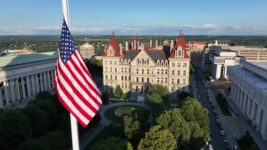 Patriotic American flag in west capitol park of Albany city. Sunset time in American town. New York State capitol and Chancellor Hall building in center of city. Aerial view. Proud and pride city.
