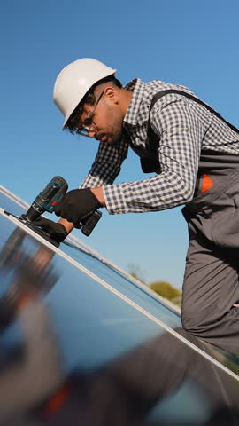 Middle eastern technician installing solar panel on roof on sunny day
