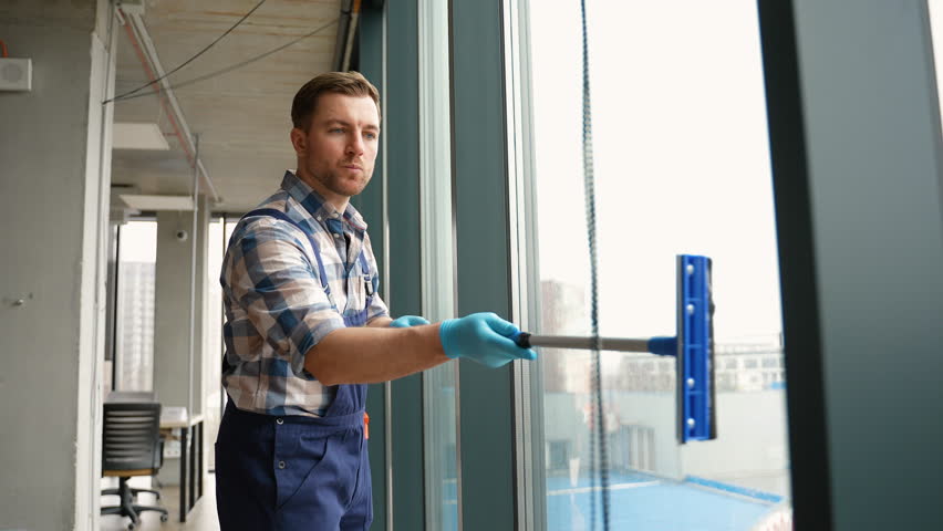 Professional cleaning service washing office windows with squeegee