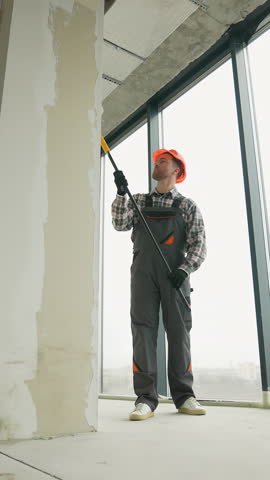 Painter applying primer on walls in new apartment