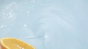 Closeup of an orange slice splashing into clear water with a swirling motion - Powered by Shutterstock - Get 15% off with code: PIKWIZARD15