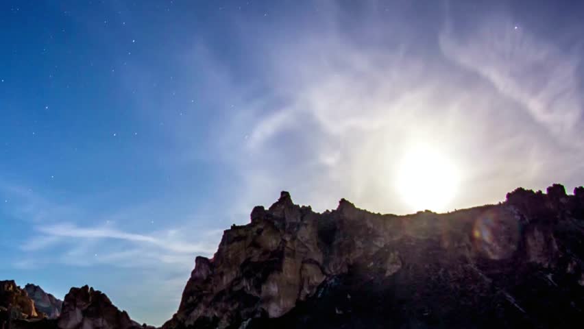 Majestic mountain range under a starry night sky with a bright moon shining
