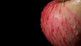 Side view macro of apple skin with red stripes and droplets, rotating slowly against deep black. Crisp texture and shine on black. - Powered by Shutterstock - Get 15% off with code: PIKWIZARD15