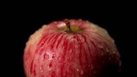 Close macro of a red-streaked apple rotating on black. Glossy droplets highlight freshness. - Powered by Shutterstock - Get 15% off with code: PIKWIZARD15